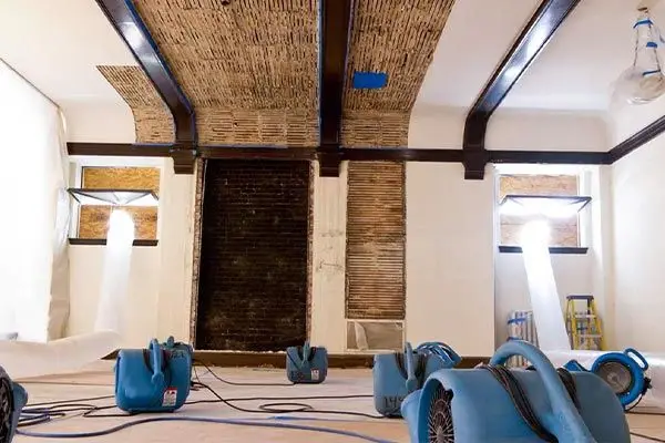 Air movers drying a water-damaged room with exposed lath ceiling