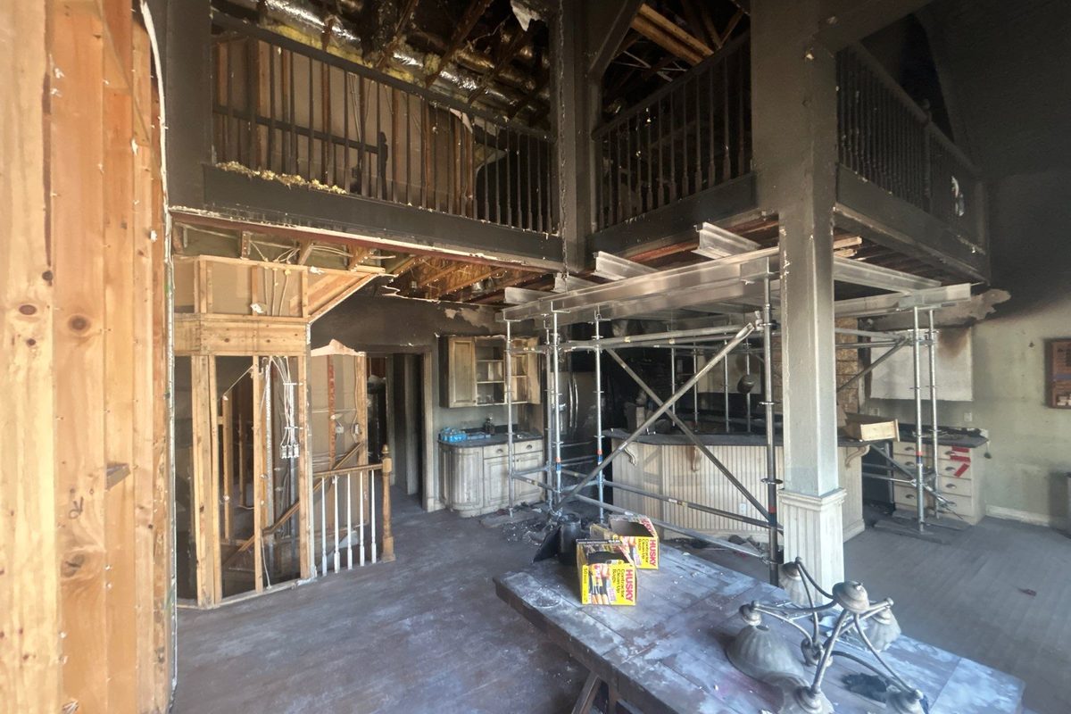 Fire damaged home interior with charred framing, soot covered walls, and scaffolding set for reconstruction