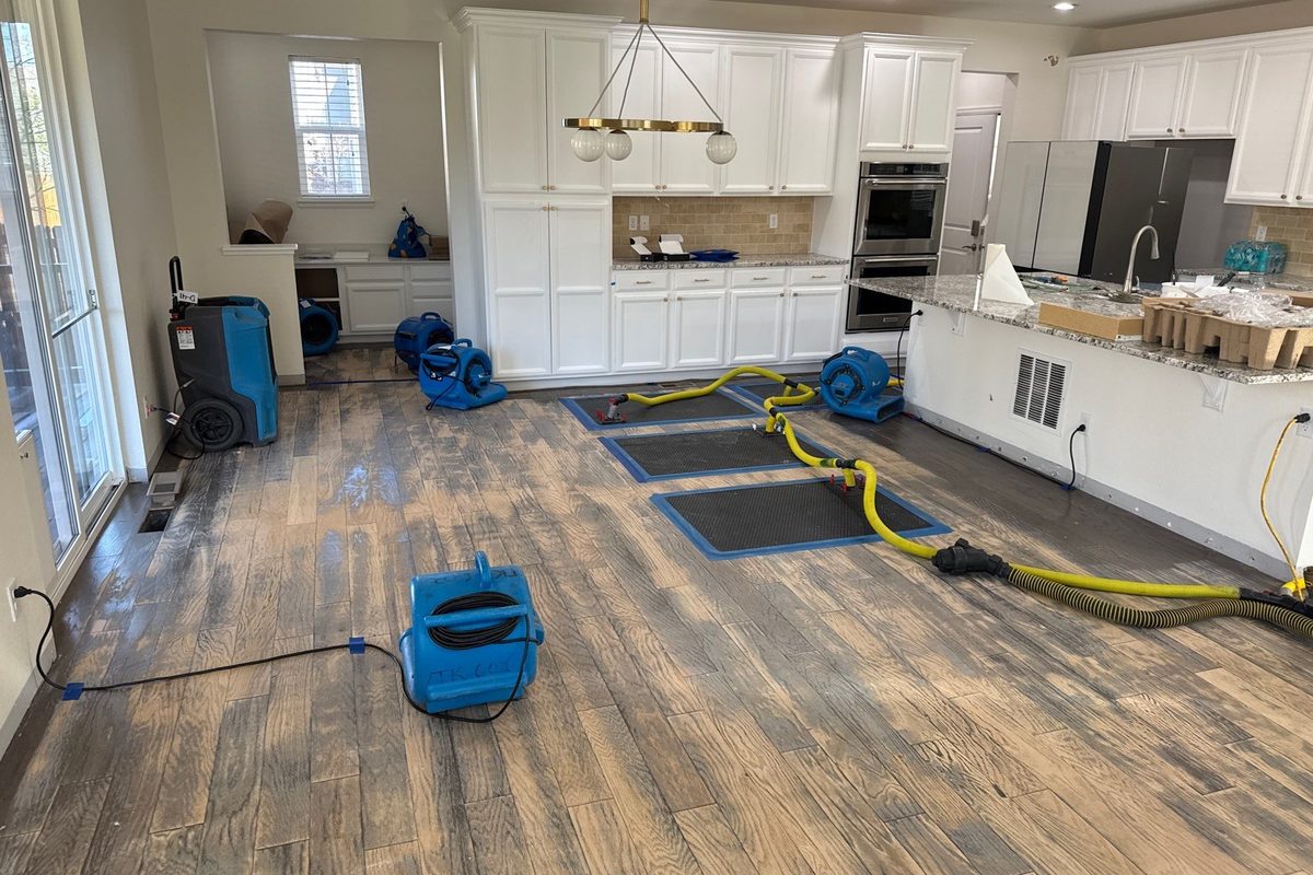 Air movers and a dehumidifier drying a water damaged Denver home kitchen and great room after a pipe leak.