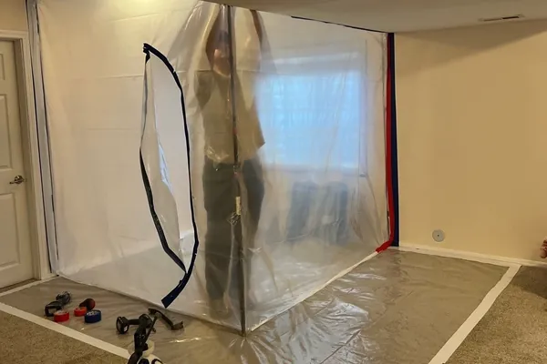 Forefront technician applying antimicrobial inside poly containment during mold remediation in a Colorado basement