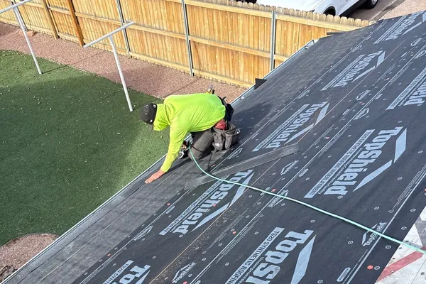 Forefront roofer fastening synthetic underlayment during a residential roof replacement