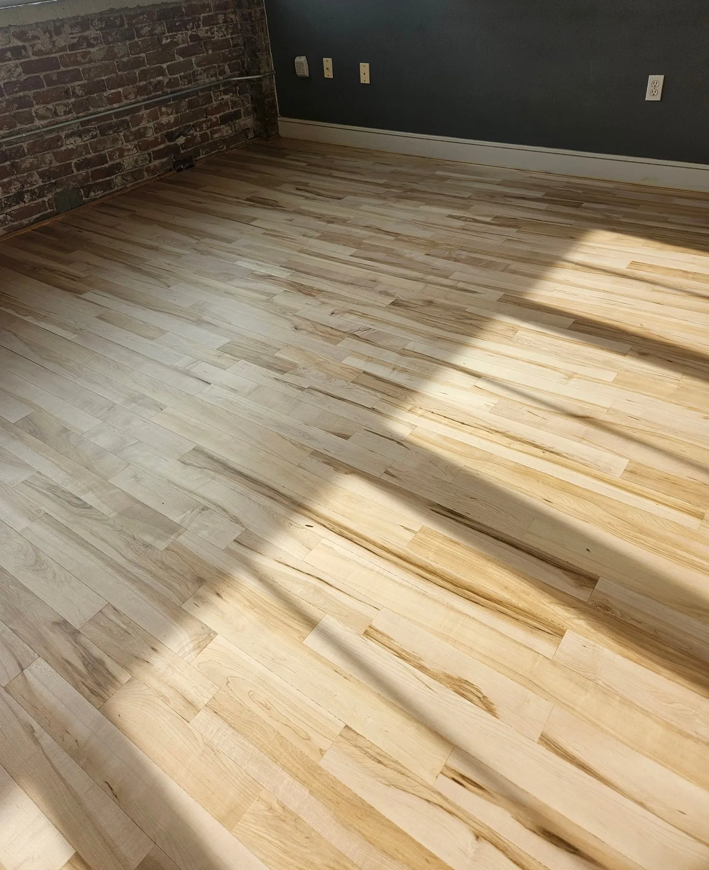 Refinished hardwood floors against exposed brick in a restored home