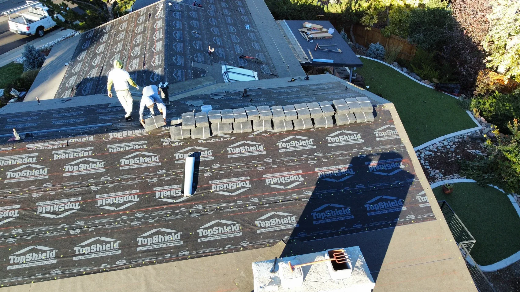 Crew installing new underlayment and shingles during a Colorado roof replacement