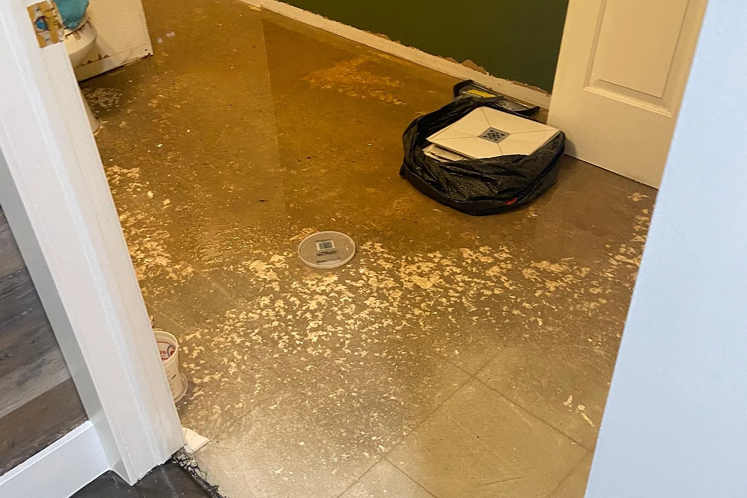 Sewage-contaminated bathroom floor with residue and a floor drain during assessment