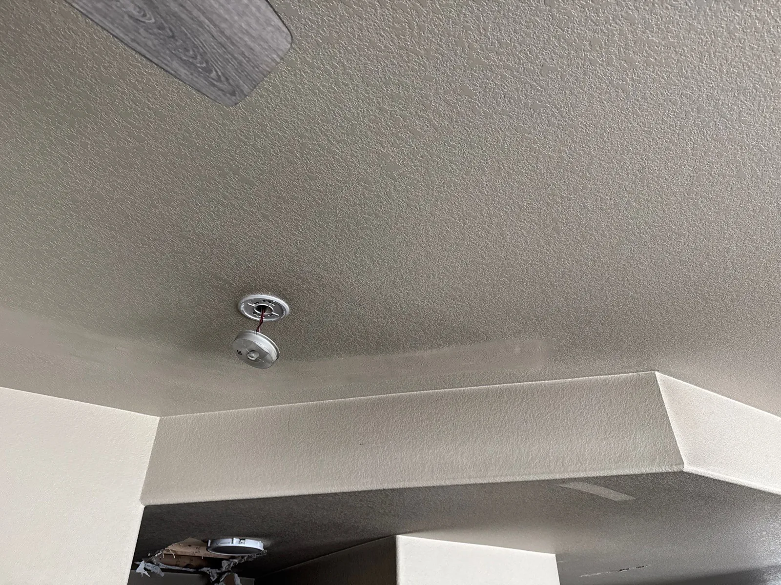 Faint soot discoloration spread across a ceiling in a room away from the fire