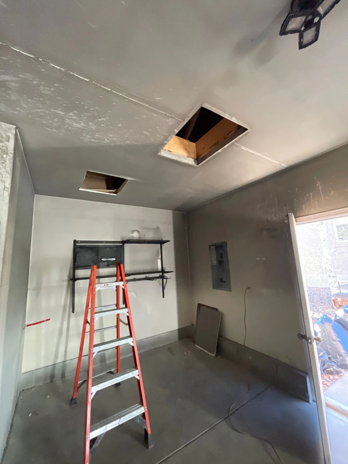 A garage coated in grey soot film with the ceiling opened up during smoke cleanup