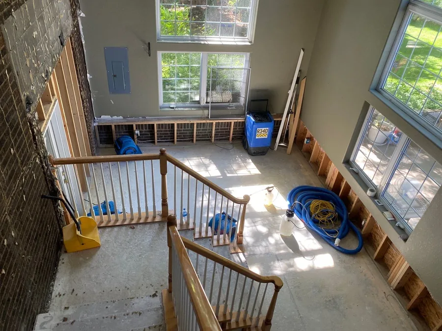 Two-story residential foyer mid-restoration with flood-cut walls, a dehumidifier, and drying equipment after water damage.