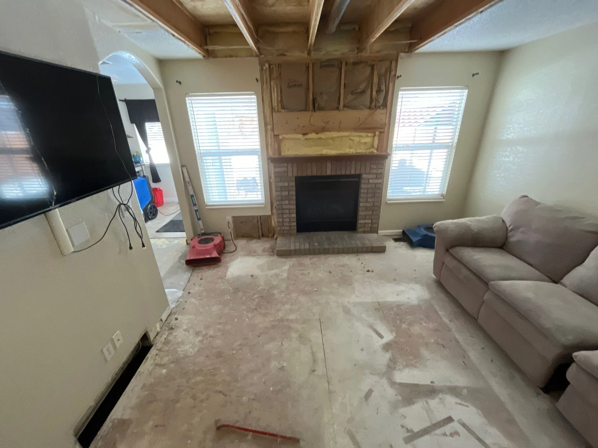 A living room mid-mitigation with a red air mover and dehumidifier set up for structural drying during water damage restoration