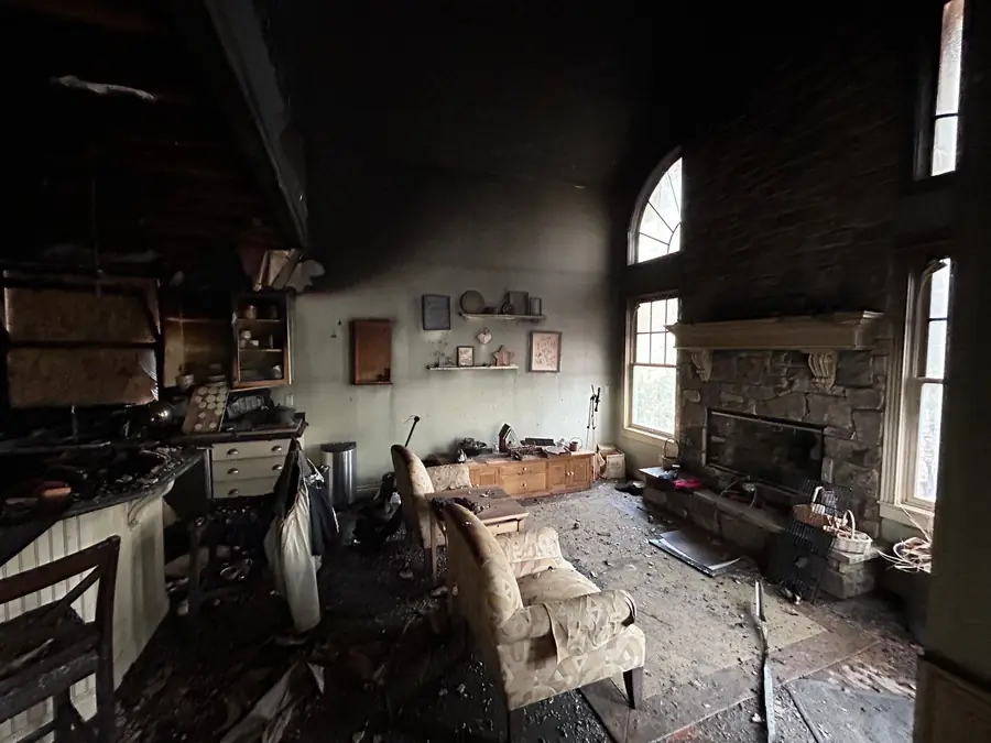Fire and smoke damage inside a Colorado home with heavy soot on the ceiling and walls, charred furniture, and debris