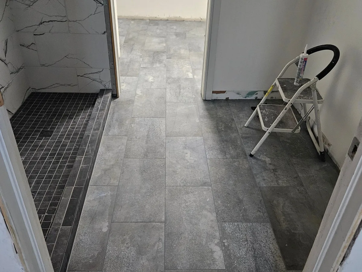 A bathroom rebuilt after sewage damage with new tile floor and a tiled shower