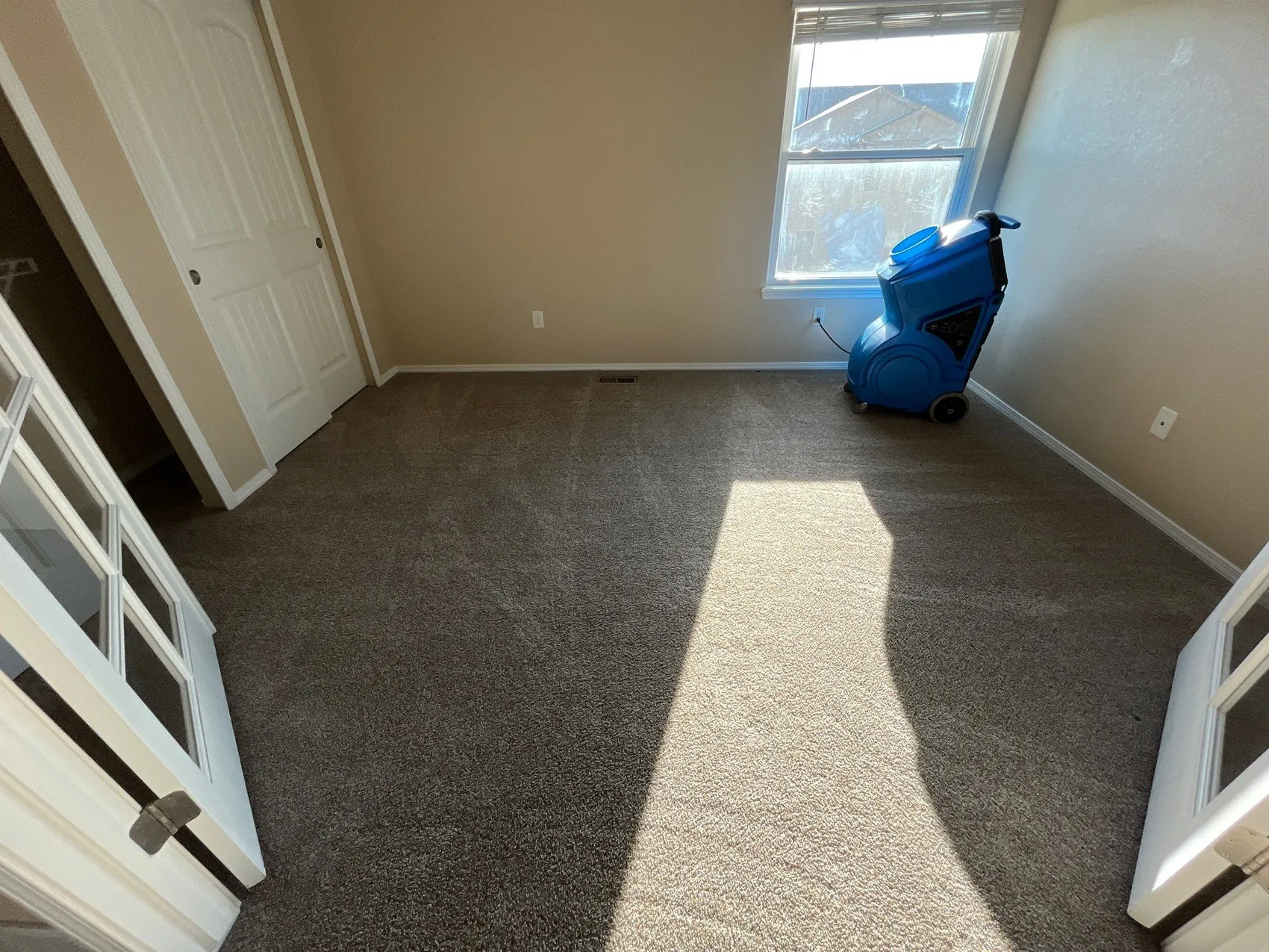 A blue air scrubber (AFD) running in a room to filter smoke and neutralize odor during smoke damage cleanup in Colorado