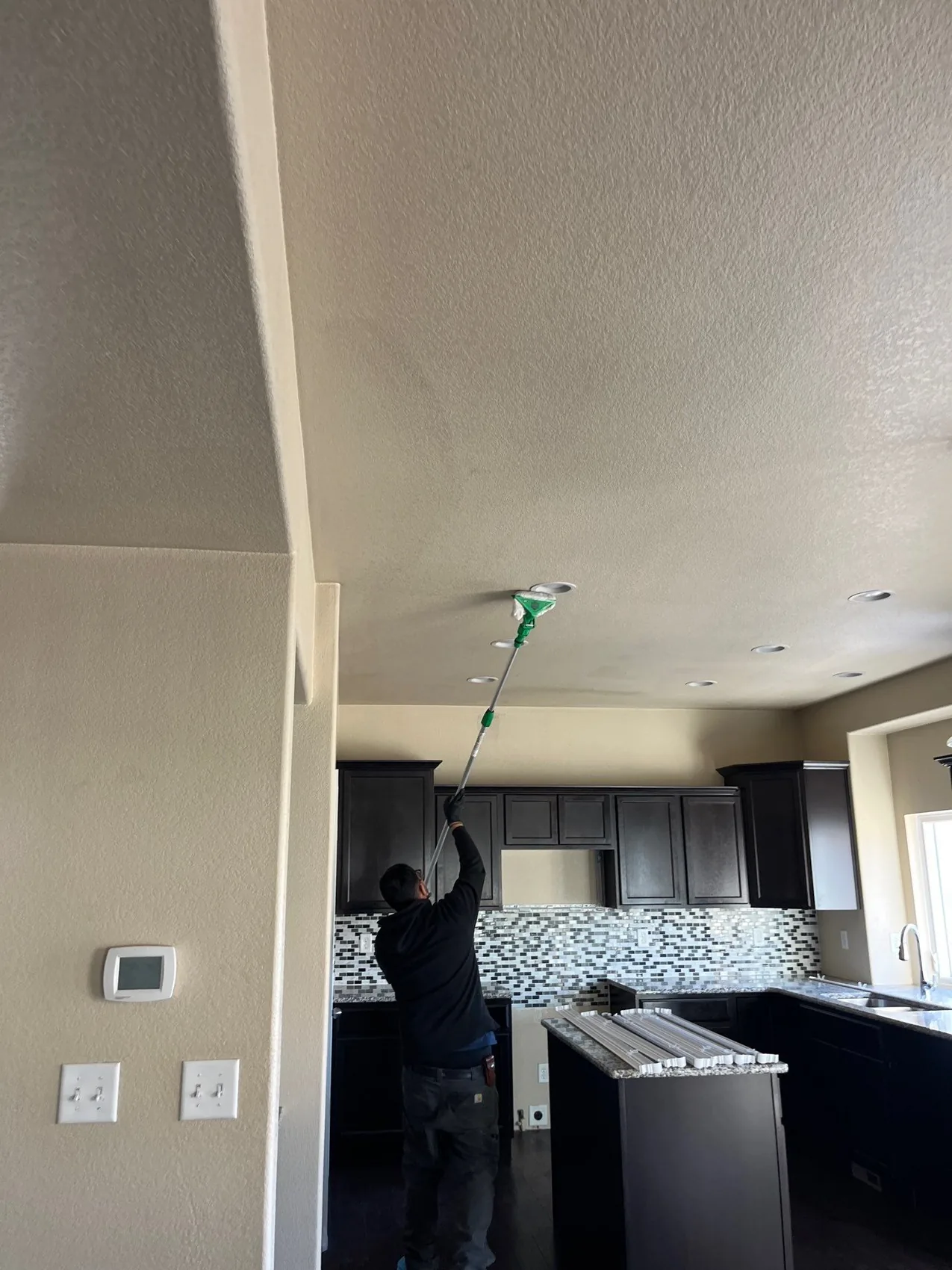 Technician cleaning soot off a kitchen ceiling during smoke damage cleanup in Colorado