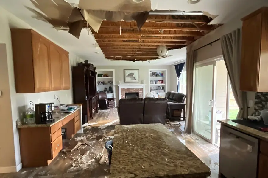 Water damage in a Colorado home with a collapsed ceiling exposing the joists and drywall debris scattered across the kitchen island
