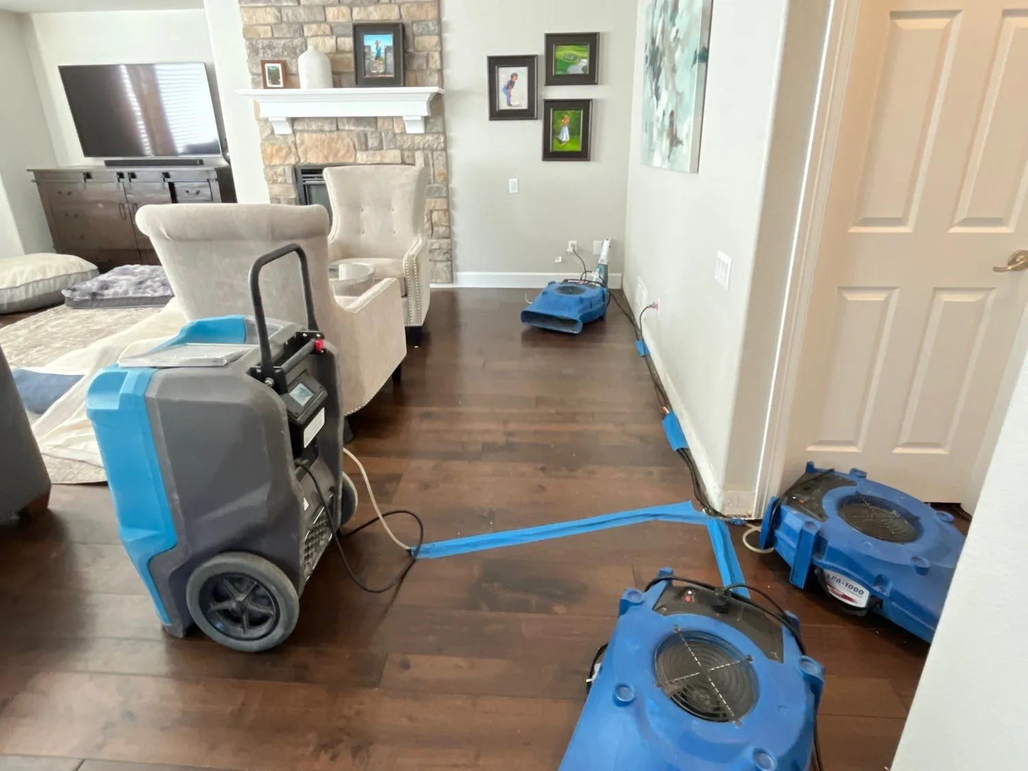 Commercial dehumidifier and air movers drying a hardwood floor after a water loss