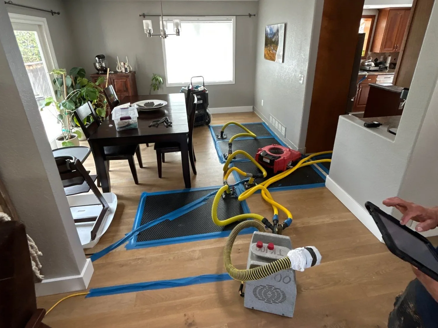 Forefront technician monitoring floor-drying mats and an air mover during a water mitigation project