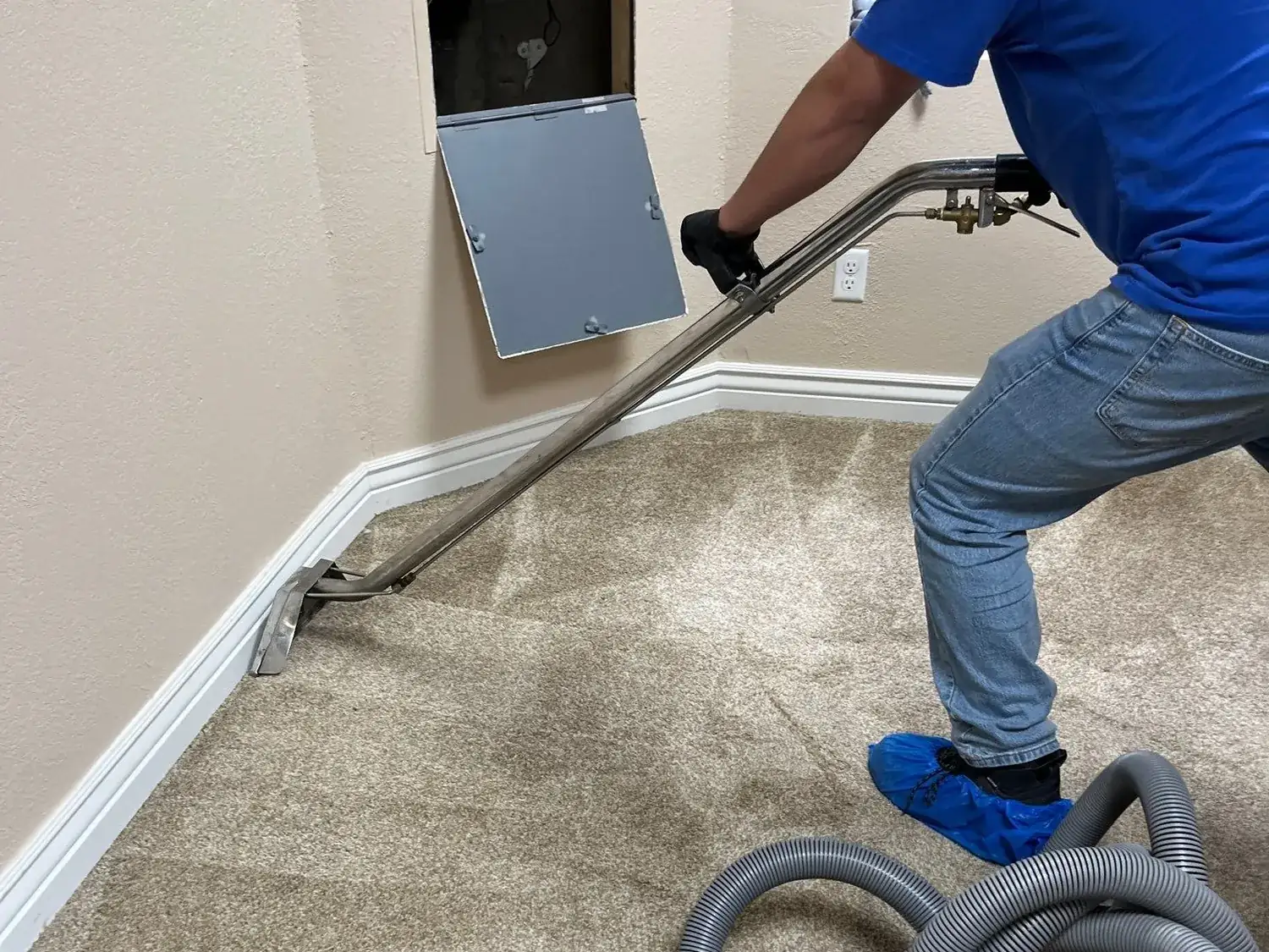Restoration technician extracting water from soaked carpet with a truck-mounted extraction wand