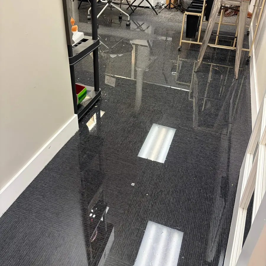 Standing water spread across carpet tile after a supply line break