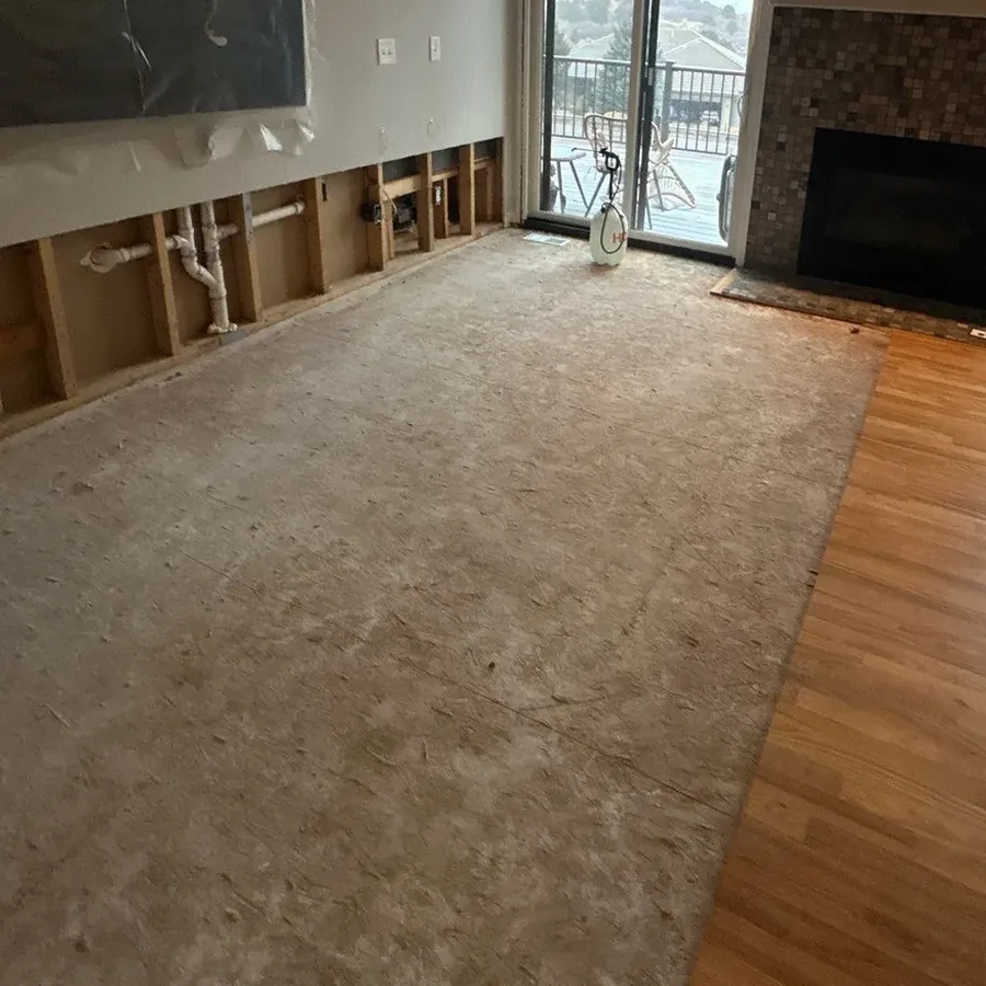 Water damaged flooring removed to expose the subfloor, next to hardwood that stayed in place